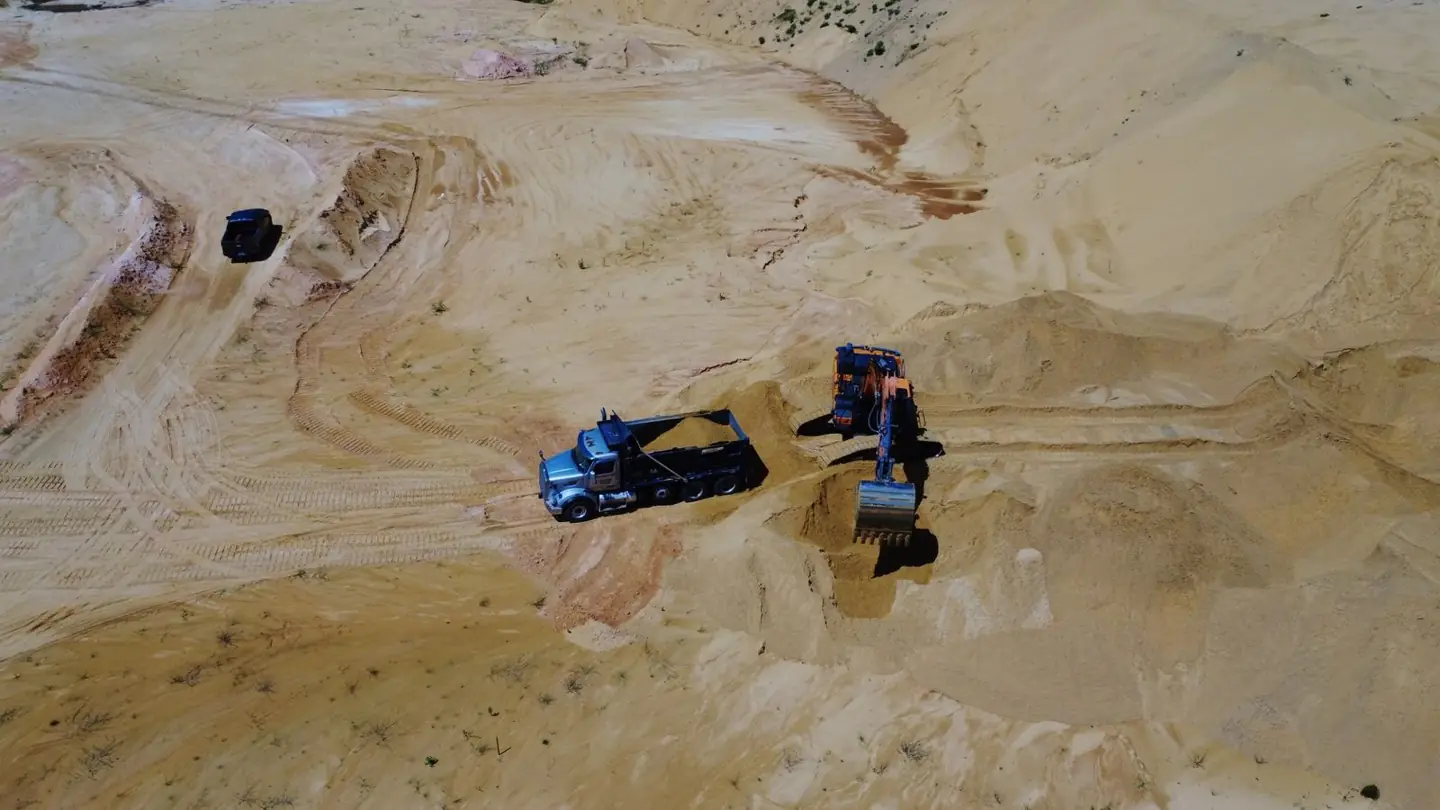 Excavator loading fill material into a dump truck at a Central Florida sand pit