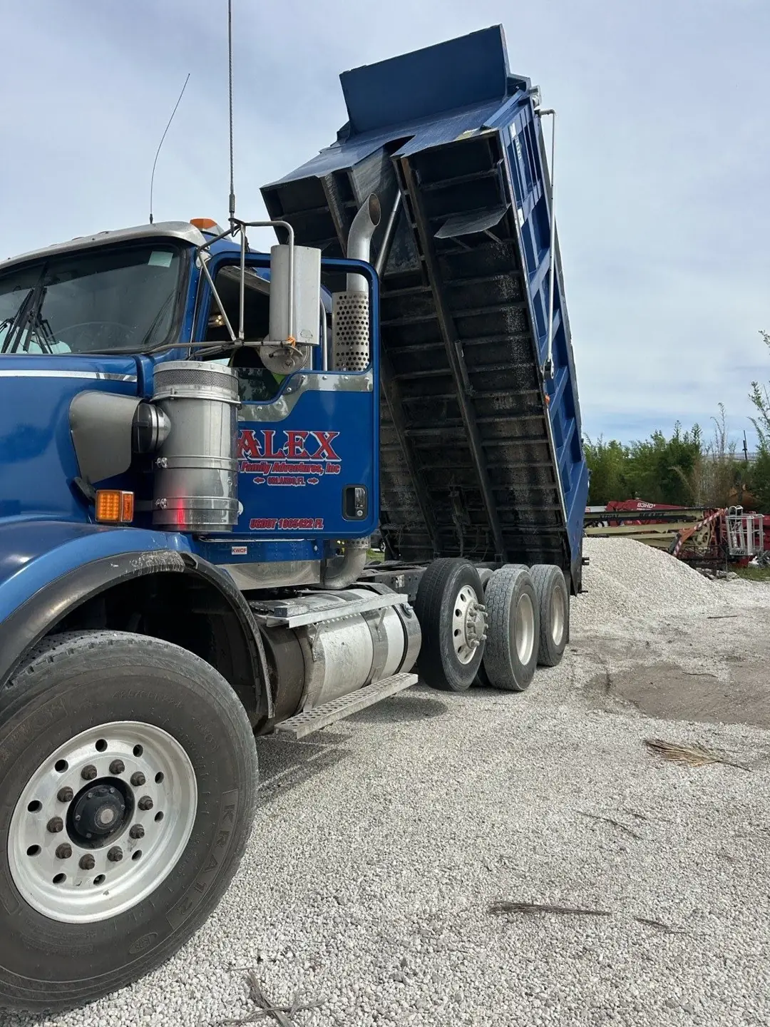 Blue dump truck with raised bed dumping FDOT #57 limestone aggregate in Central Florida